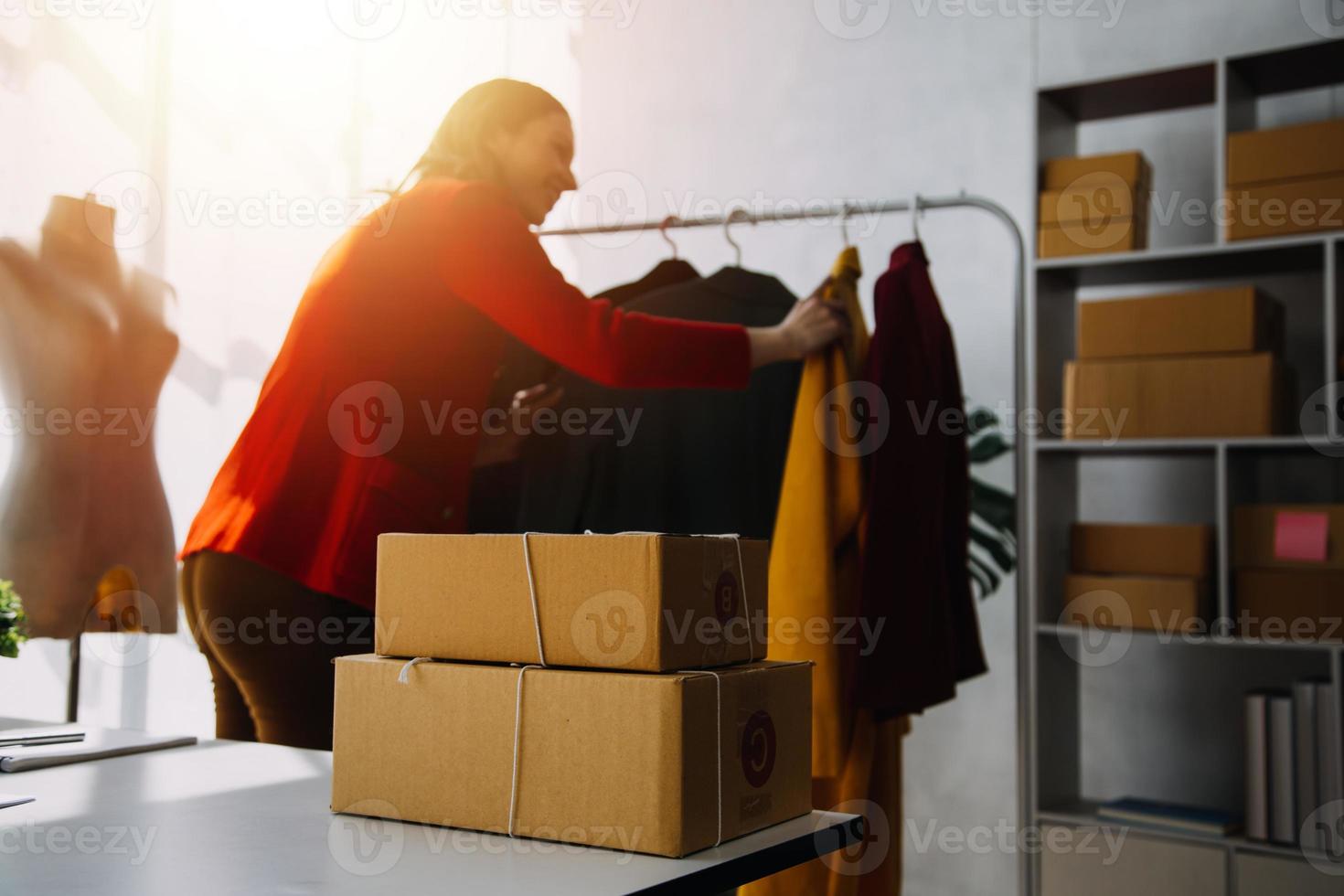 Beautiful lady blogger showing clothes in front of the camera to recording vlog video live streaming at her shop. Online Shopping Cart notion. photo