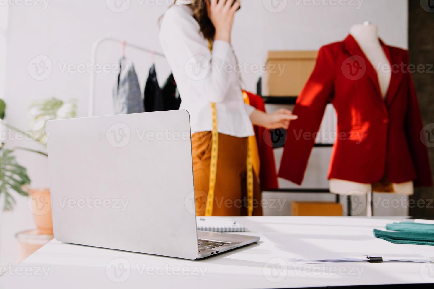 Beautiful lady blogger showing clothes in front of the camera to recording vlog video live streaming at her shop. Online Shopping Cart notion. photo