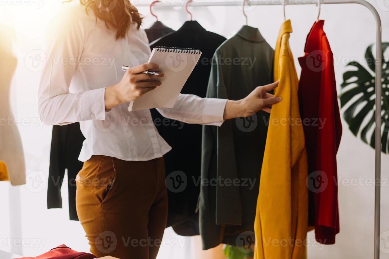 Beautiful lady blogger showing clothes in front of the camera to recording vlog video live streaming at her shop. Online Shopping Cart notion. photo