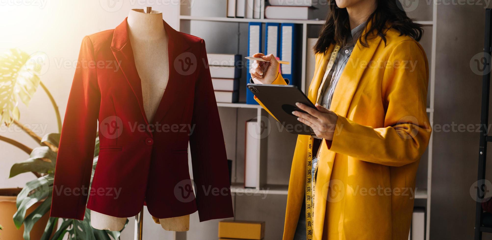 Beautiful lady blogger showing clothes in front of the camera to recording vlog video live streaming at her shop. Online Shopping Cart notion. photo
