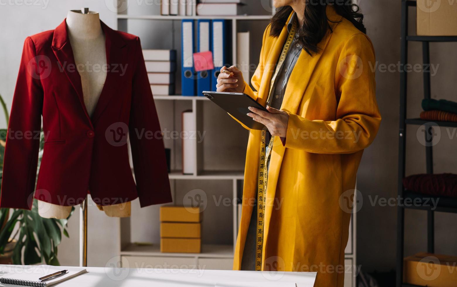 Beautiful lady blogger showing clothes in front of the camera to recording vlog video live streaming at her shop. Online Shopping Cart notion. photo