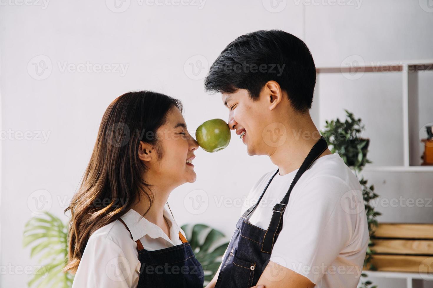 en cocina perfectamente contento Pareja preparando sano alimento, un montón de vegetales. hombre hace malabares con frutas, hace su Novia reír. encantador personas en amor tener divertido foto