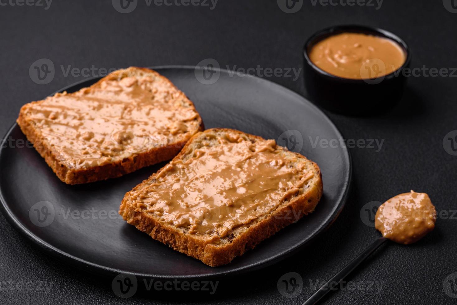 Nutritious sandwich consisting of bread and peanut butter on a black ceramic plate photo