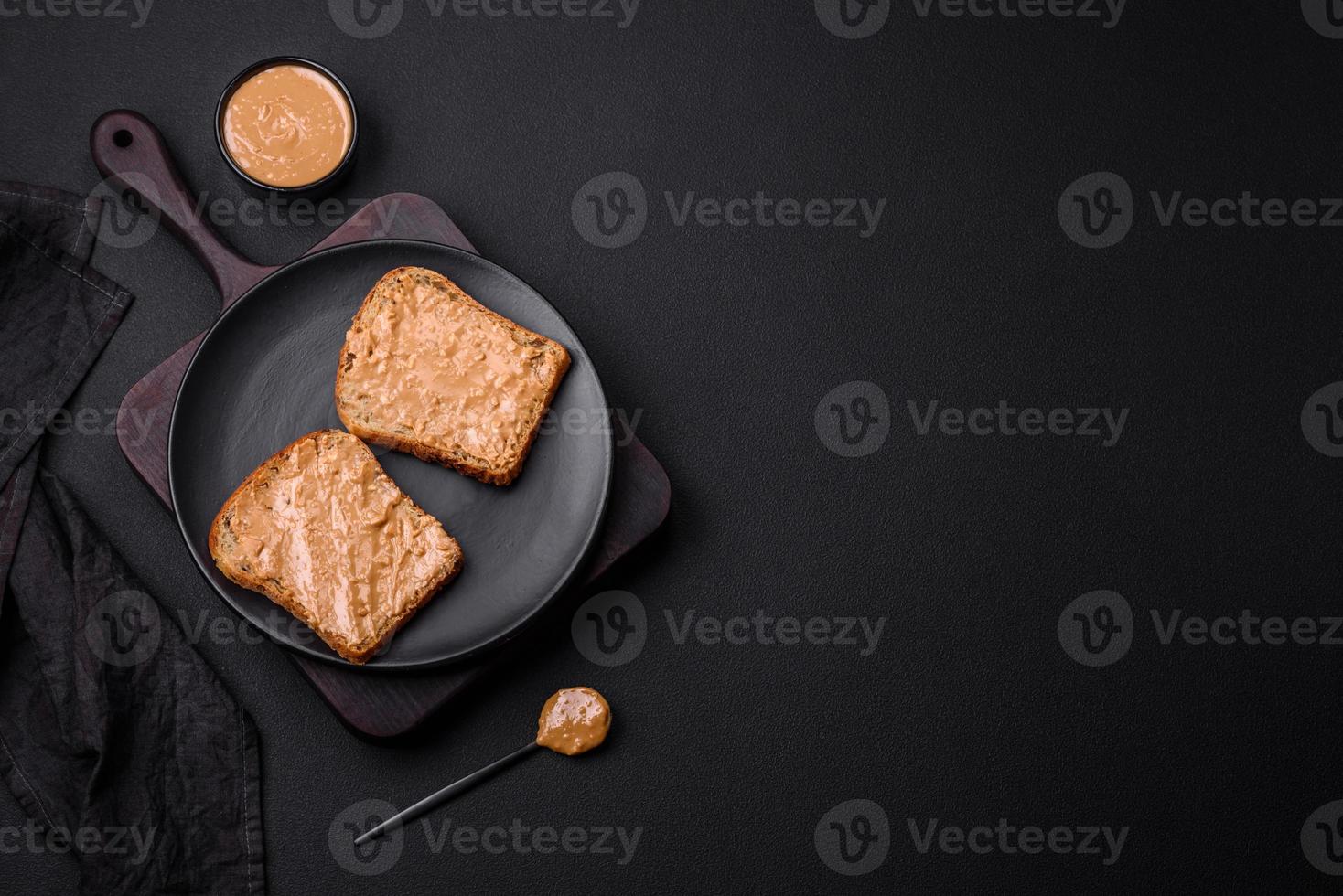 Nutritious sandwich consisting of bread and peanut butter on a black ceramic plate photo