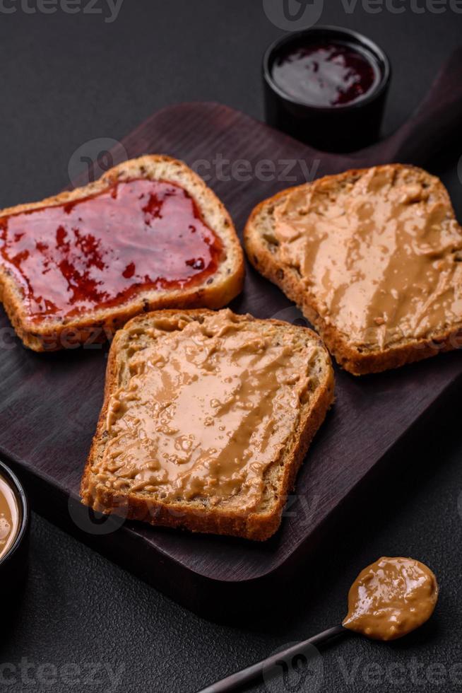 nutritivo emparedados consistente de pan, frambuesa mermelada y maní mantequilla foto
