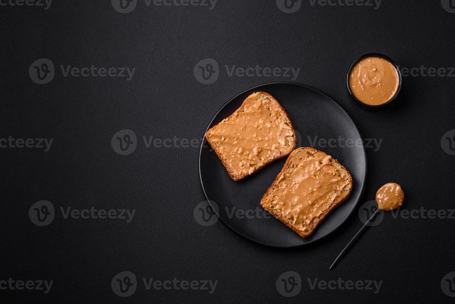 Nutritious sandwich consisting of bread and peanut butter on a black ceramic plate photo