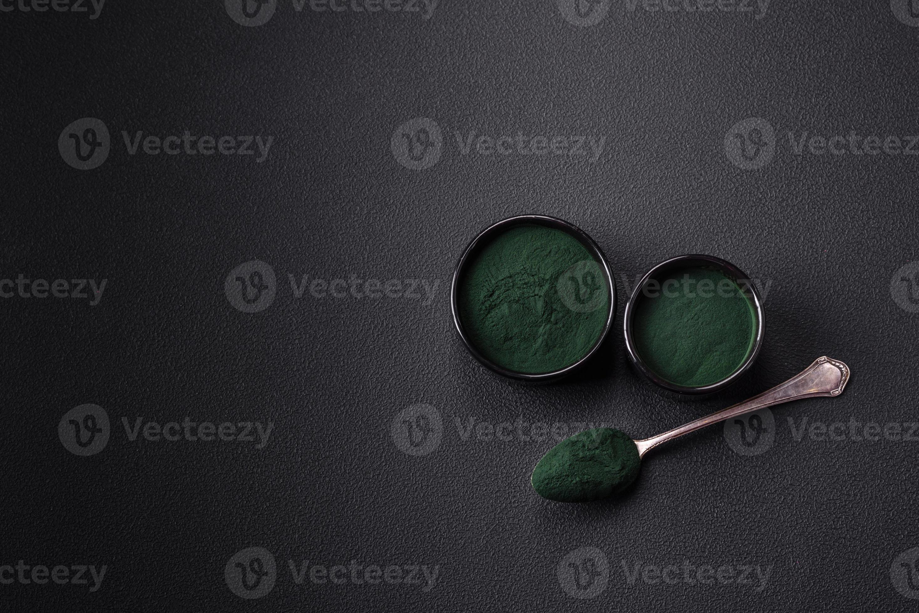 Spice, green color spirulina in the form of powder in a black bowl
