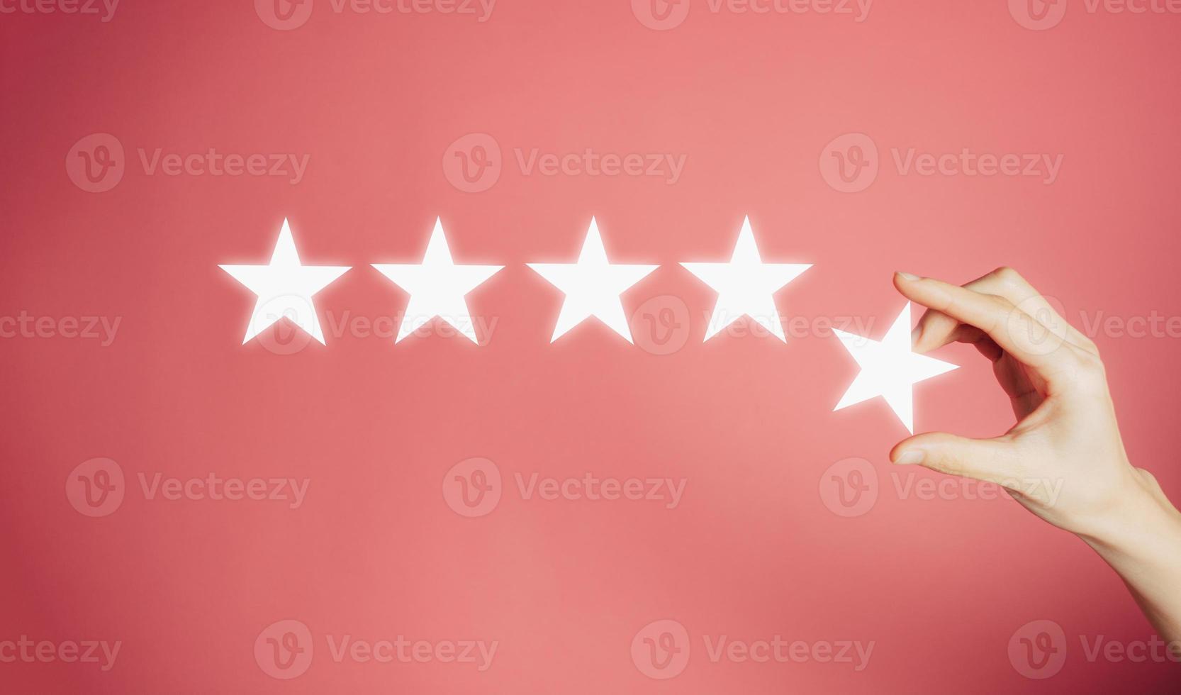 Woman's hand put the stars to complete five stars. Customer satisfaction concept. copy space and pink background. giving a five star rating. Service rating, satisfaction concept. photo