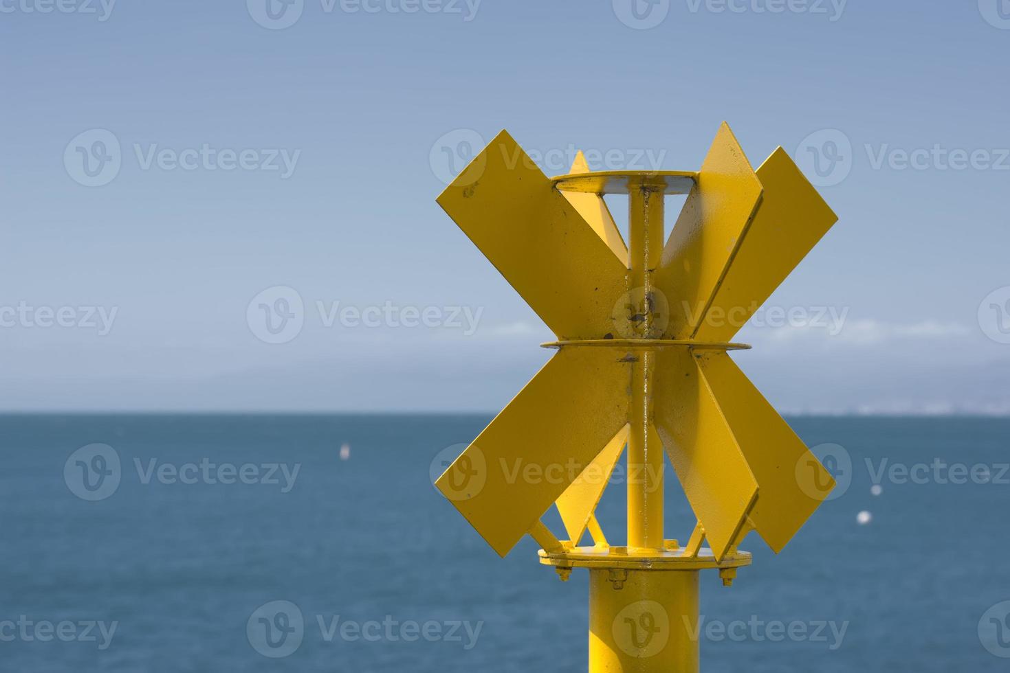Yellow no sail metallic buoy on blue sea background photo