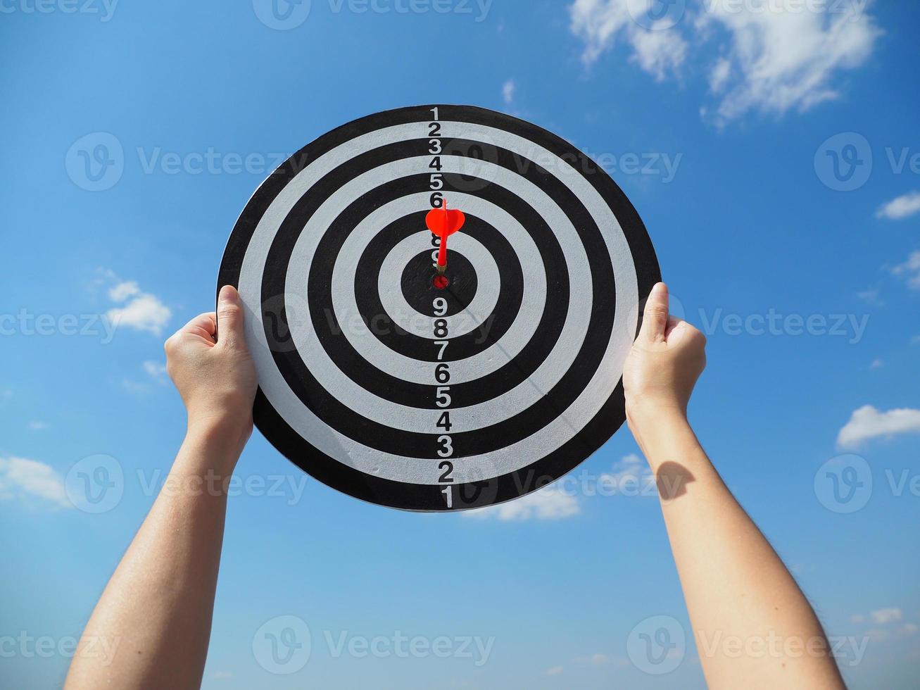 hand of a business woman holding a target business success business idea red dart in the center up in the sky photo