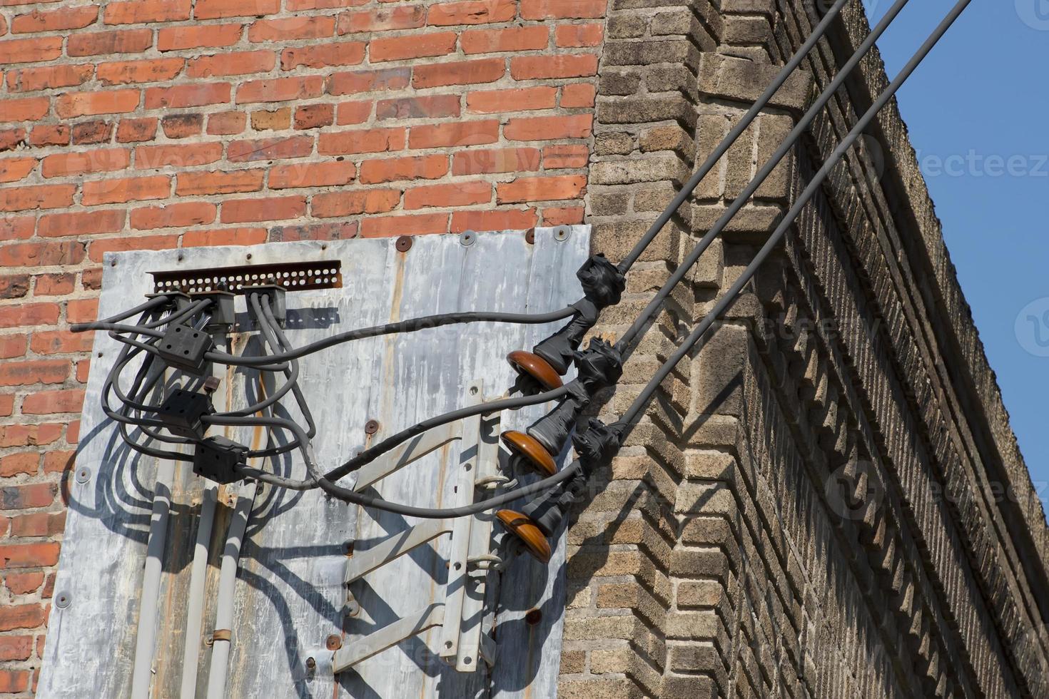 Power line cables on the red brick and blue sky background photo