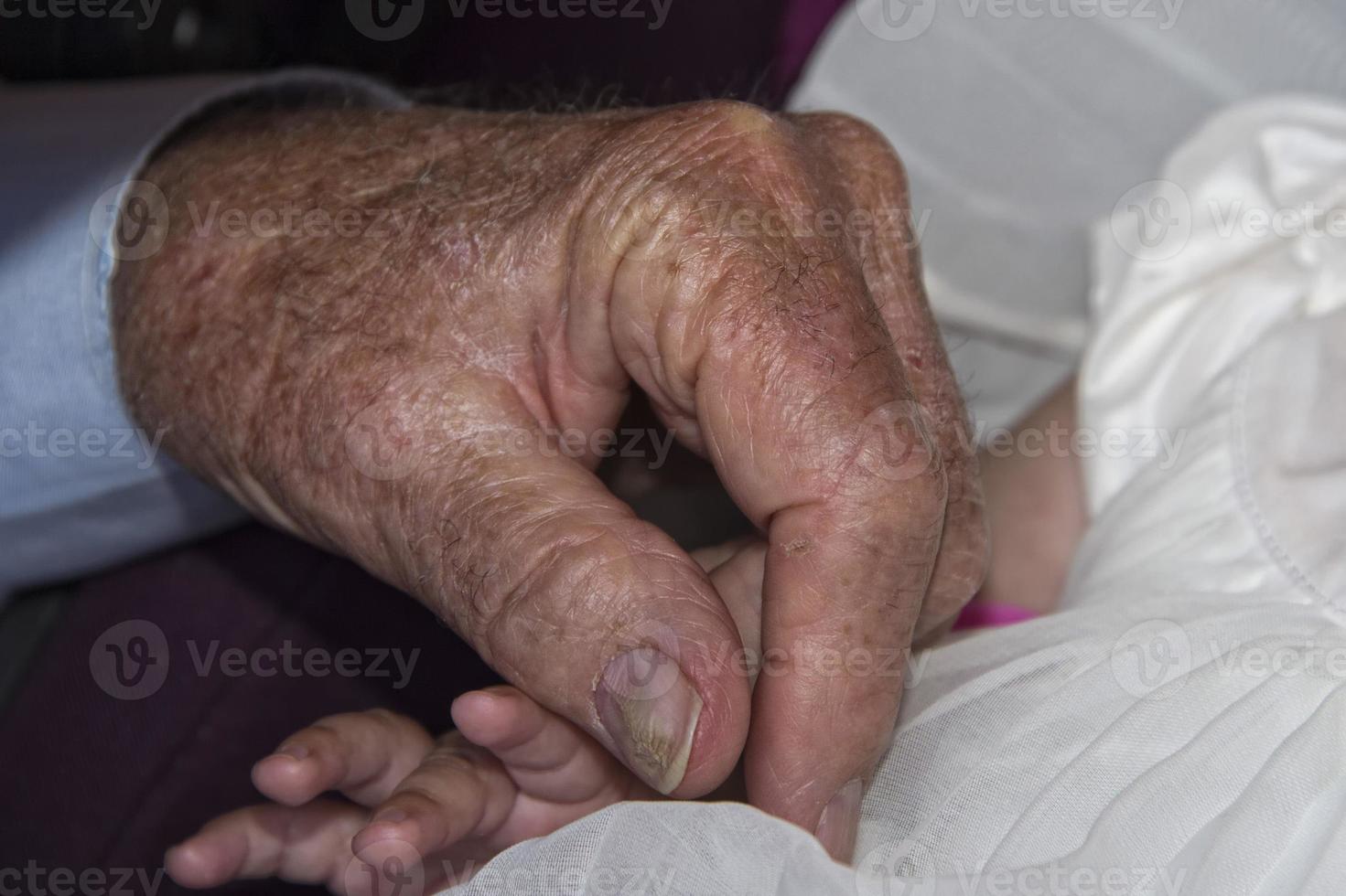 old retired man hands holding newborn infant one photo