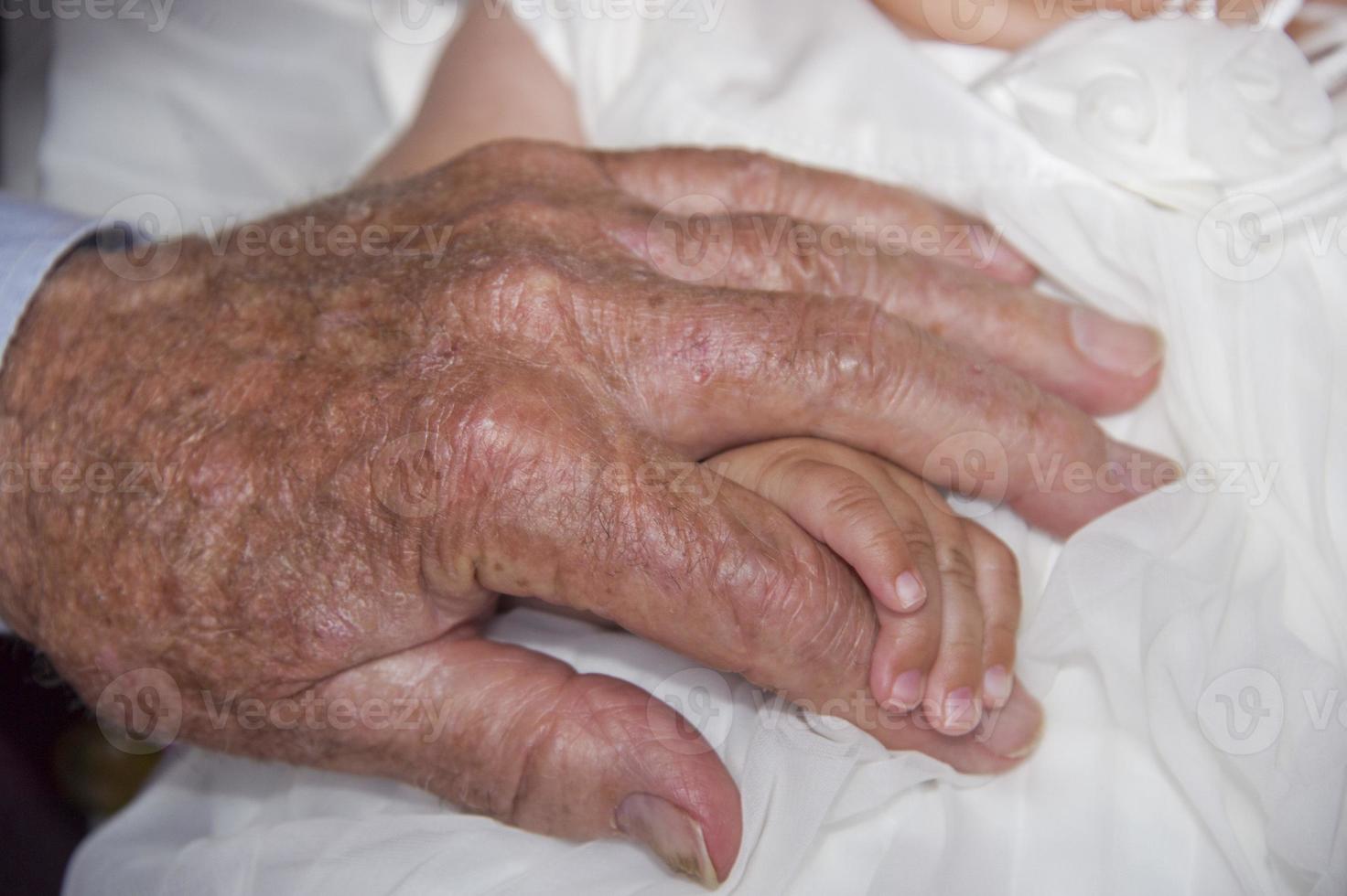 old retired man hands holding newborn infant one photo