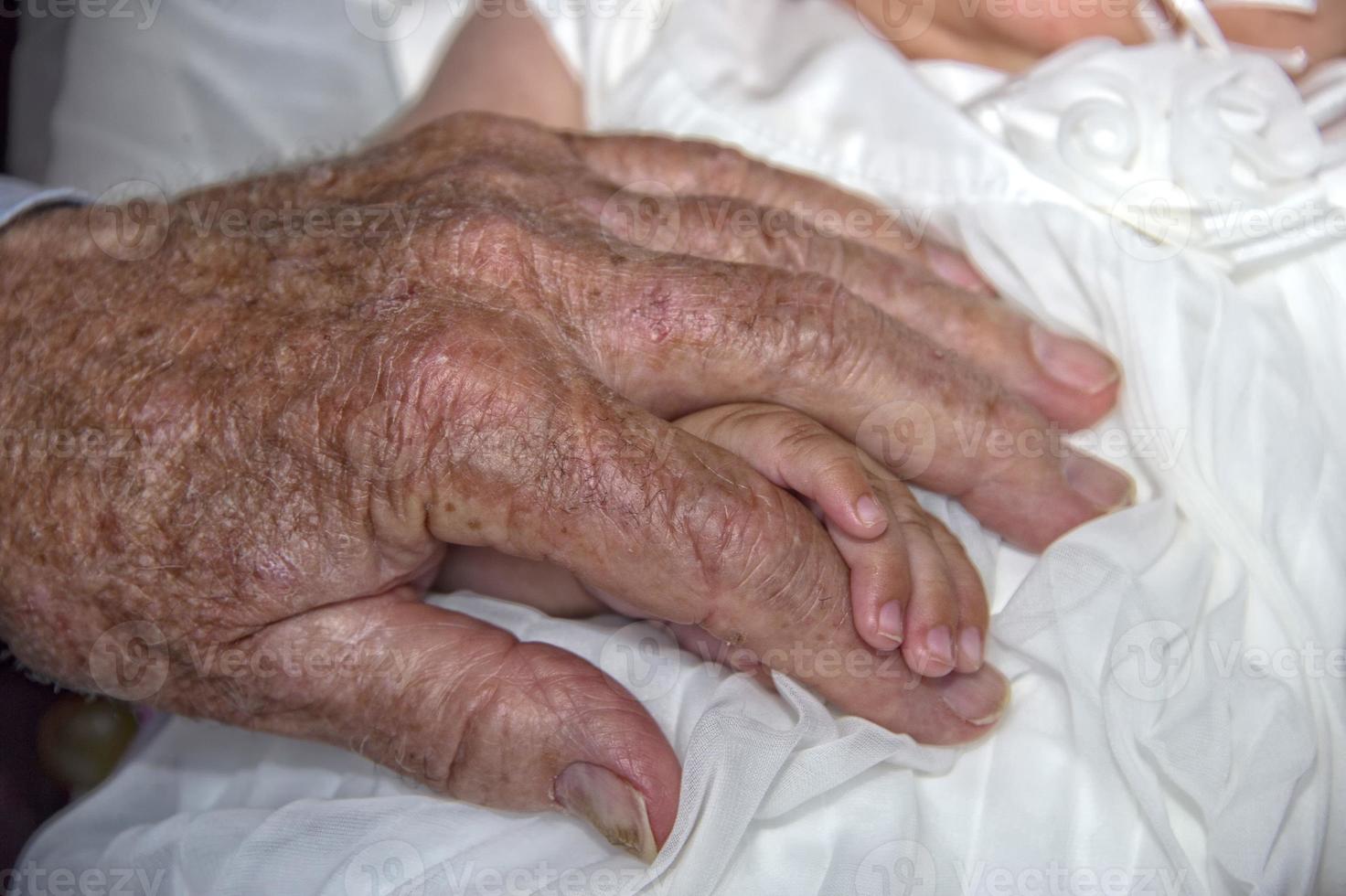 old retired man hands holding newborn infant one photo