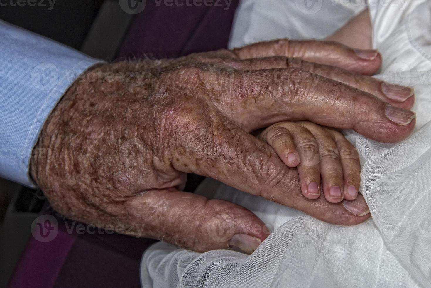 old retired man hands holding newborn infant one photo