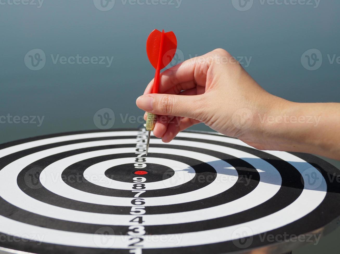 Hand of a business woman holding a red dart on a red target. business success business idea red dart in the center photo