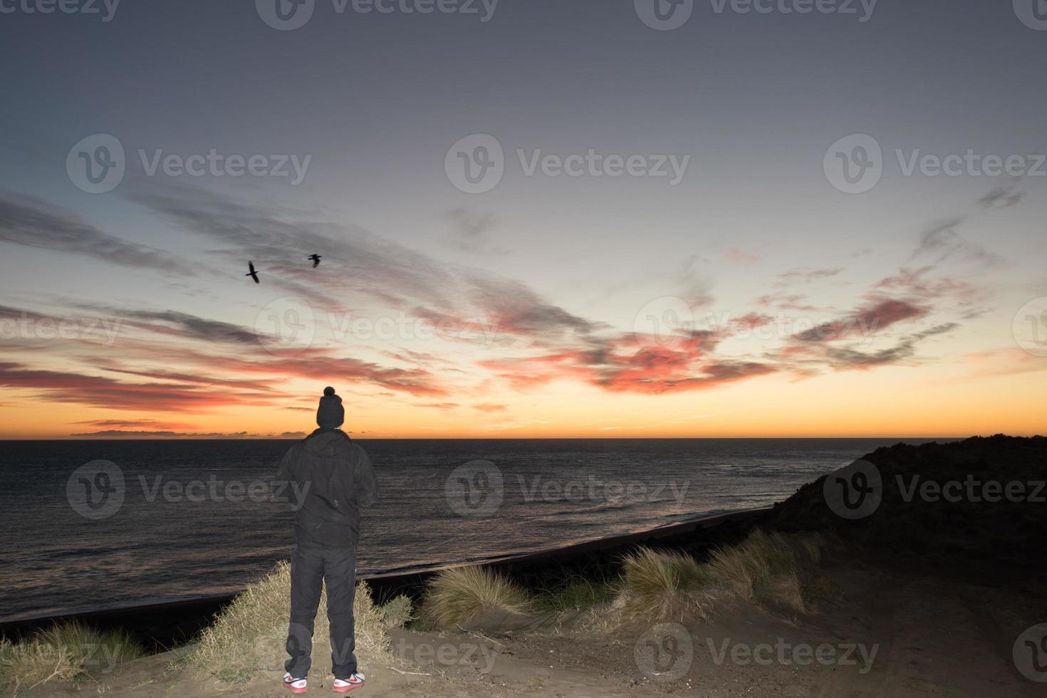 Man looking at red sunrise in patagonia beach photo