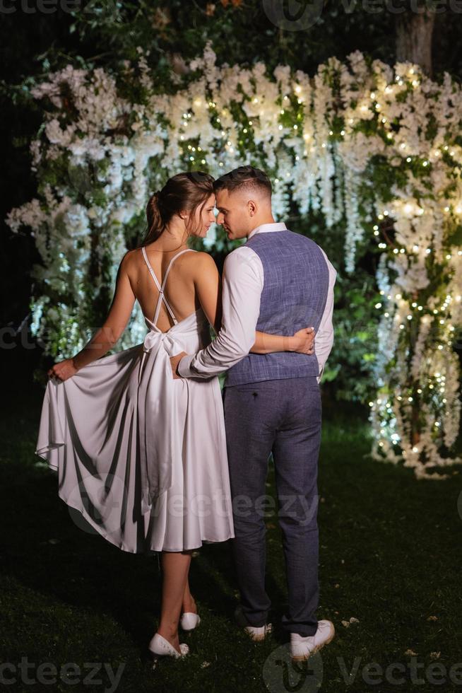 Pareja de recién casados en el noche iluminado arco foto