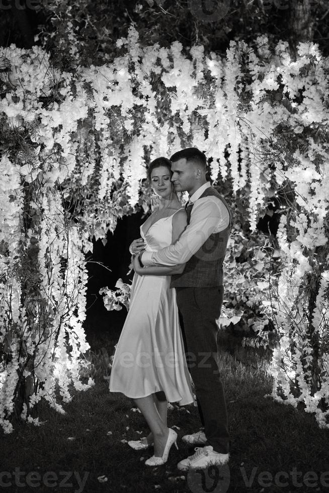 Pareja de recién casados en el noche iluminado arco foto