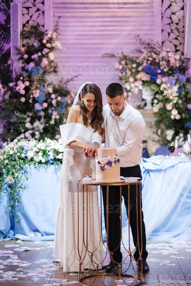 los recién casados felizmente cortan y prueban el pastel de bodas foto