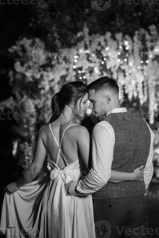 Pareja de recién casados en el noche iluminado arco foto