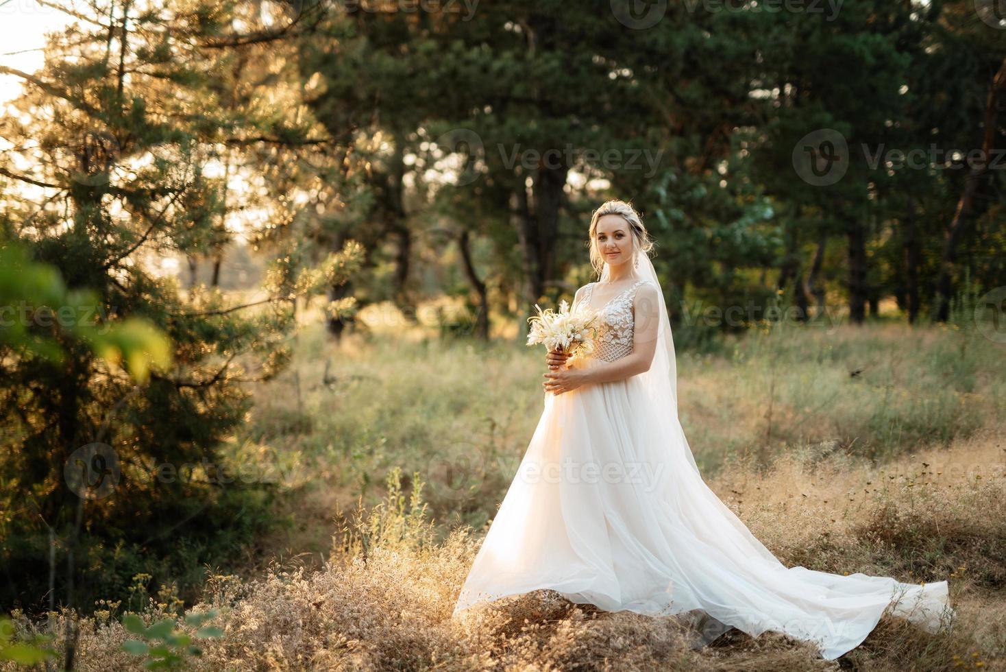 novia rubia niña con un ramo de flores en el bosque foto