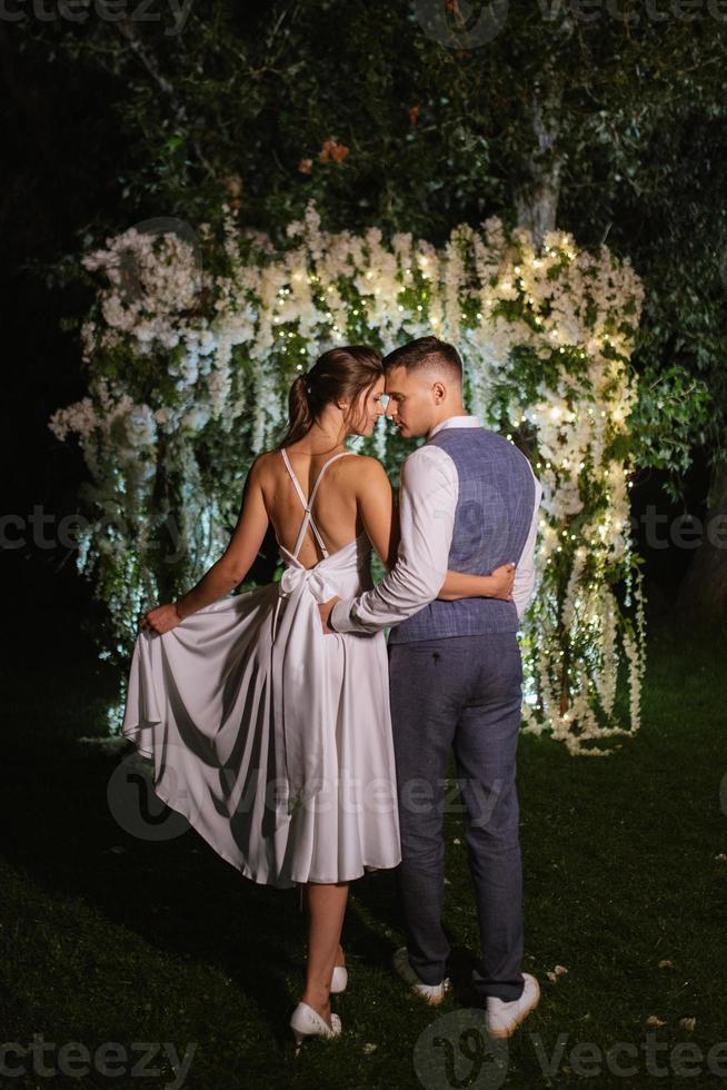 Pareja de recién casados en el noche iluminado arco foto