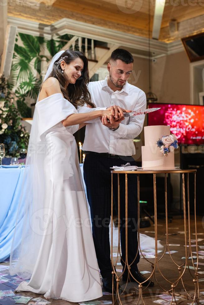 los recién casados felizmente cortan y prueban el pastel de bodas foto