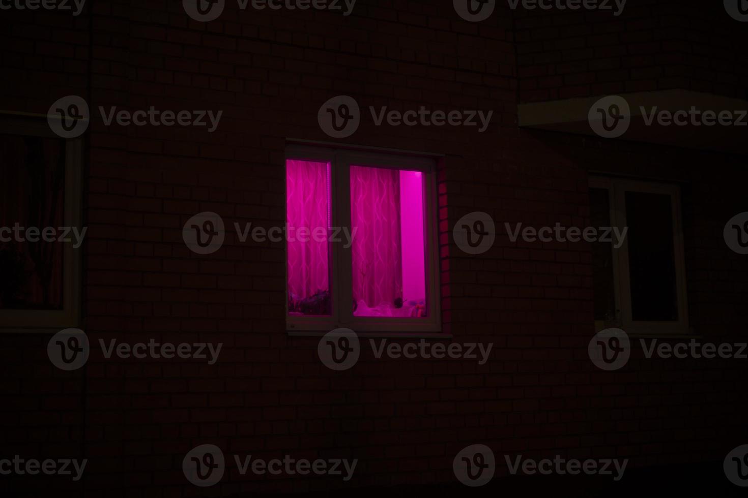 Rose window at night. Pink light in house. photo