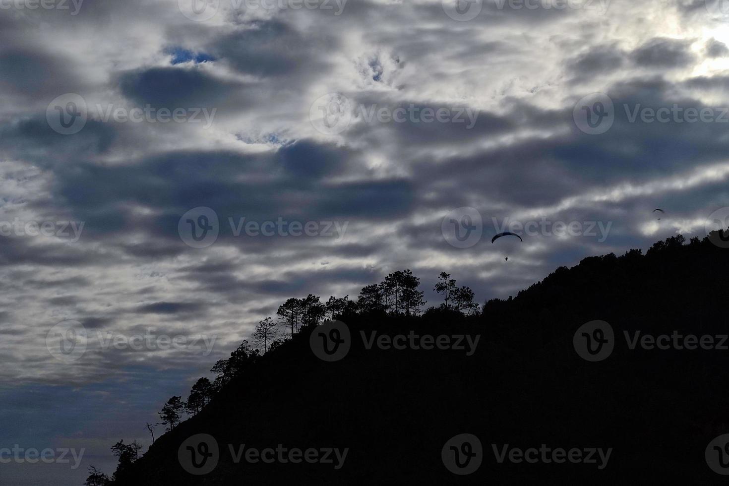 paraglider on cloudy sky in monterosso cinque terre italy photo