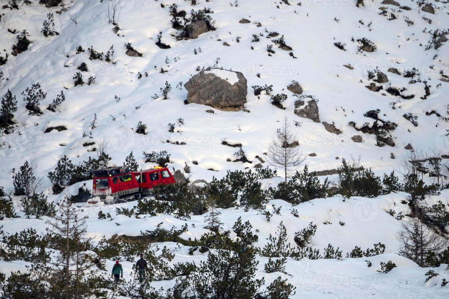 red tracked snowmobile detail climbing fanes mountain in dolomites on white snow photo