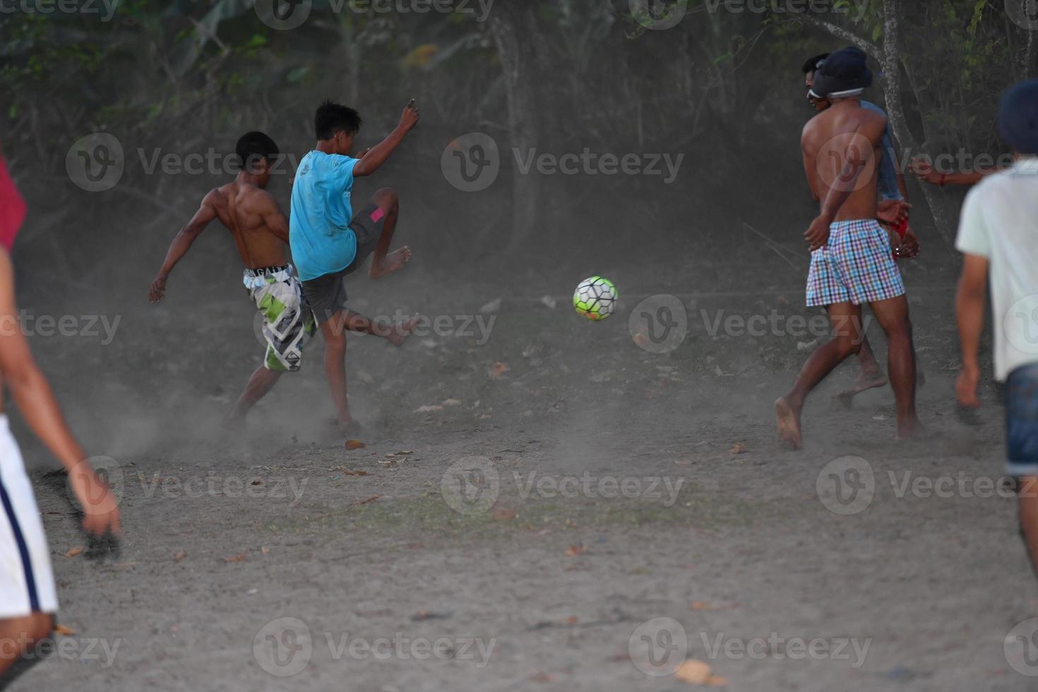 gili asahan, indonesia - 22 de agosto de 2016 - los niños juegan al fútbol al atardecer en un campo de palmeras cerca de la playa foto