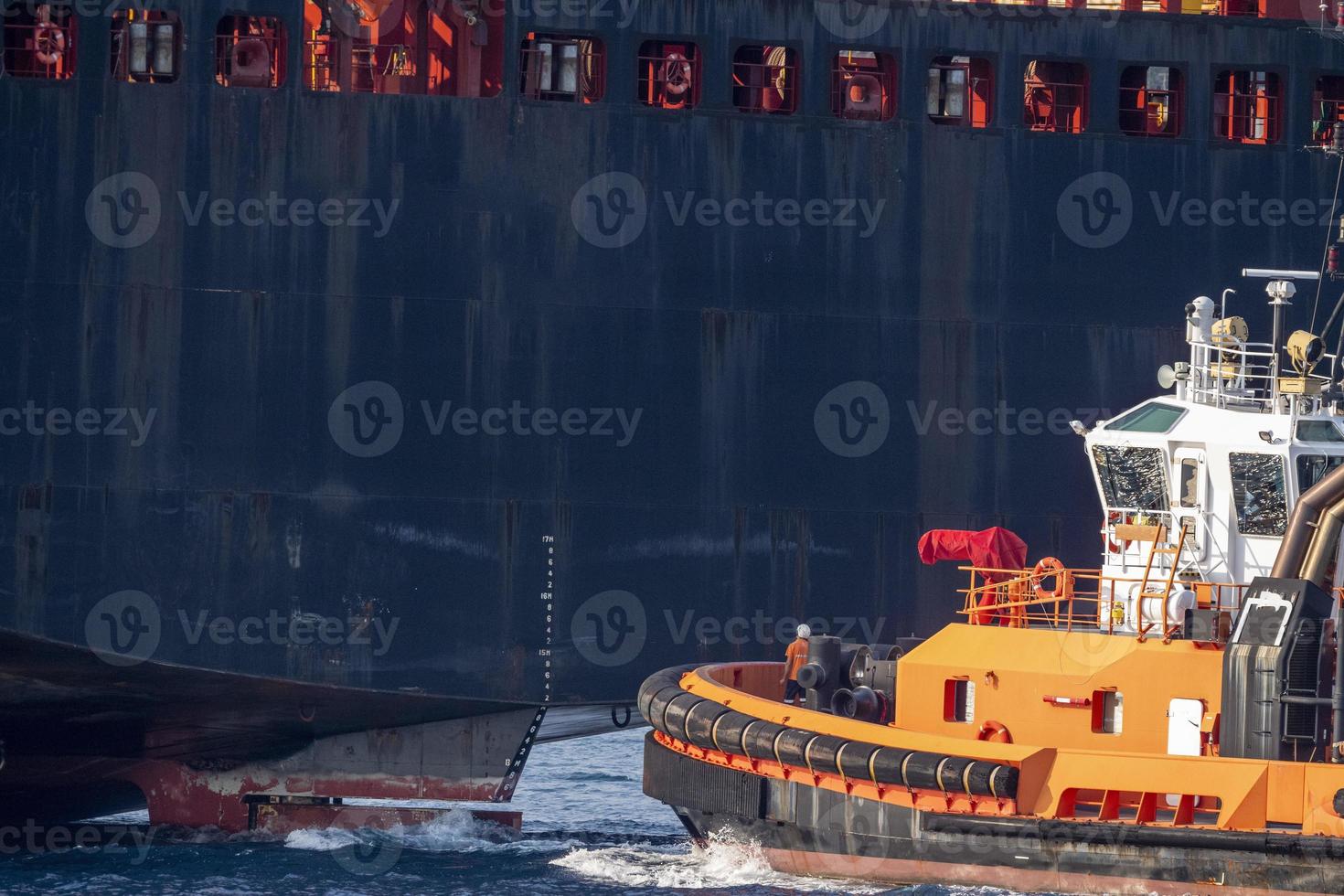 tug boat near big ship stern photo