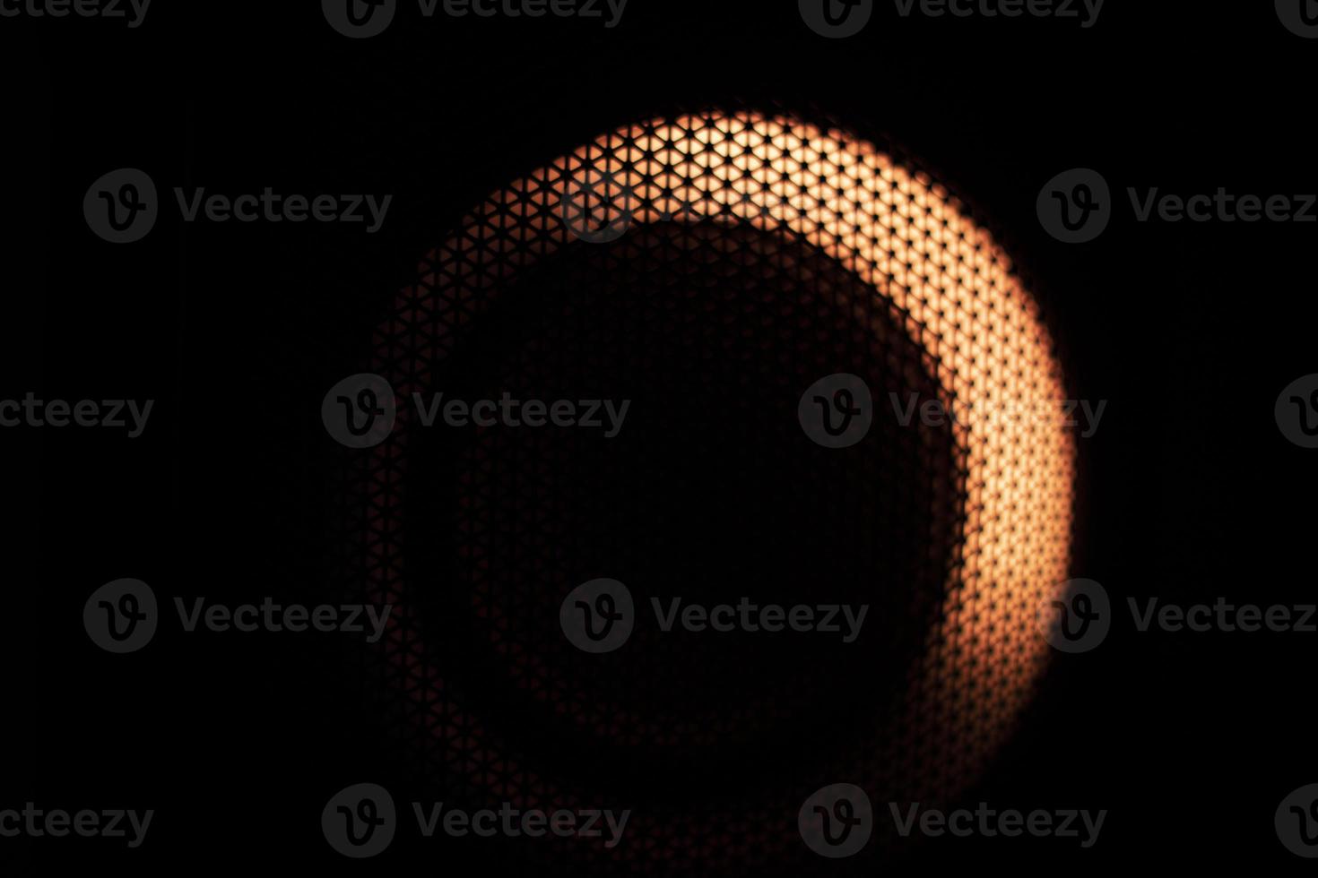 Orange light in dark. Glow through grid. Dots on black background. photo
