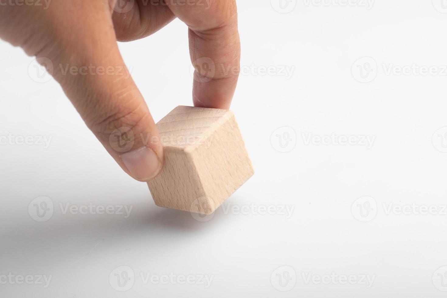 Hand holding a wooden block with a question mark on a white background photo