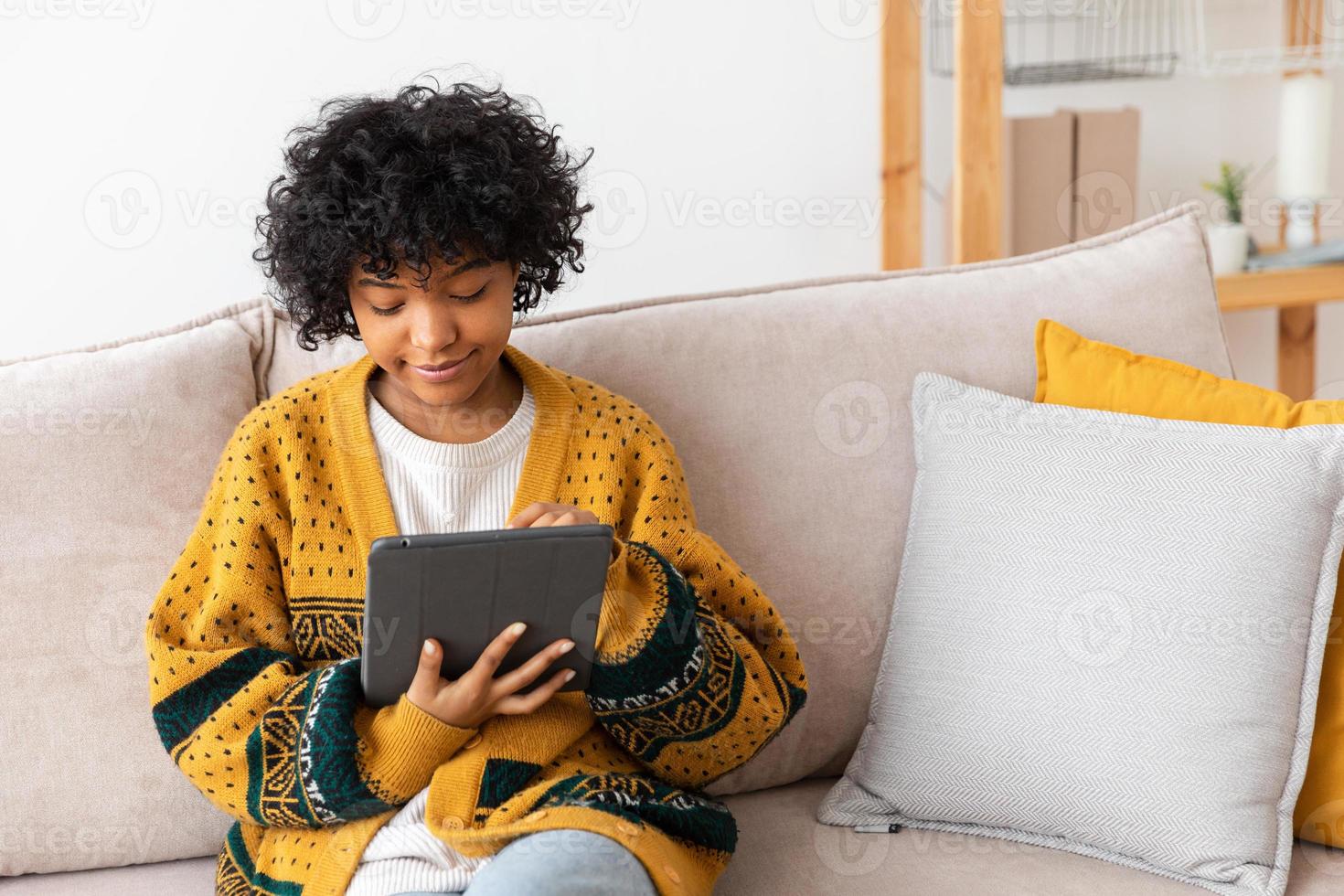 African american girl holding digital tablet touch screen typing scroll page at home. Woman with mobile tech device surfing internet using social media apps playing game. Study work shopping online. photo