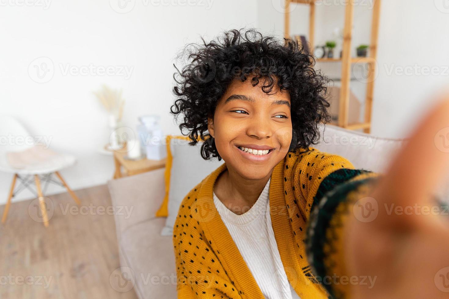 Happy african american teen girl blogger smiling face talking to webcam recording vlog. Social media influencer woman streaming making video call at home. Headshot portrait selfie webcamera view. photo