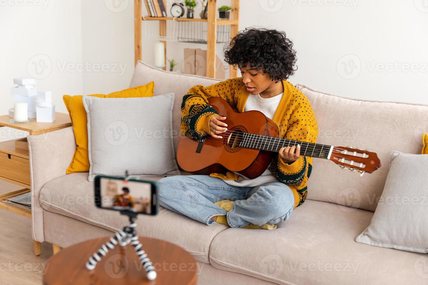 blogger guitarrista. africano americano niña blogger jugando guitarra hablando a cámara web grabación vlog. social medios de comunicación hombre de influencia mujer transmisión a hogar adentro. música contenido creador transmitir tutorial. foto