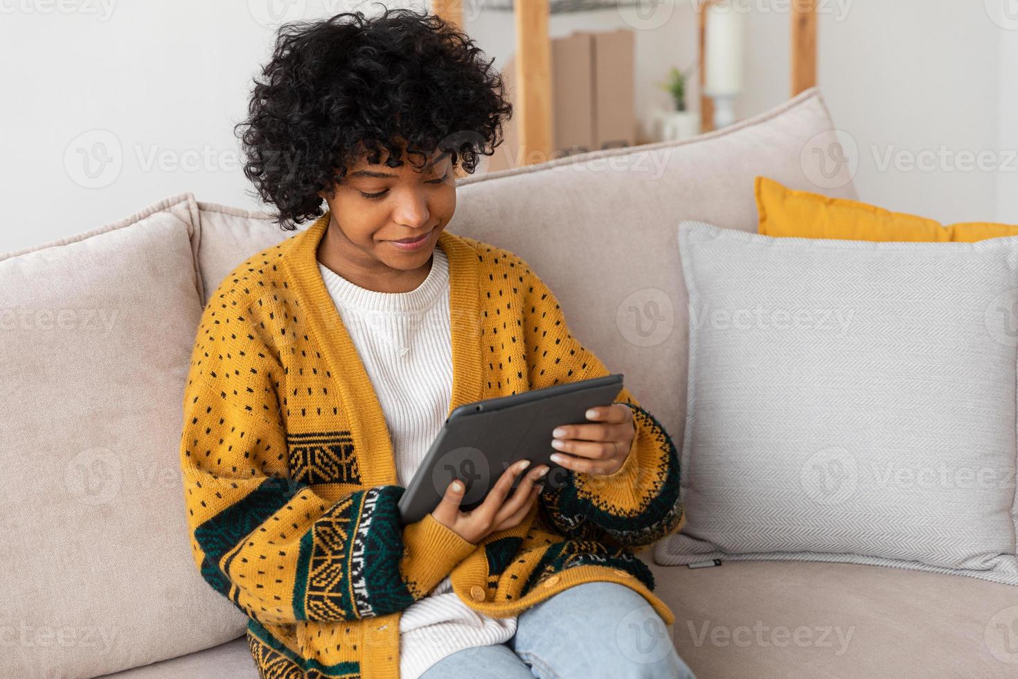 African american girl holding digital tablet touch screen typing scroll page at home. Woman with mobile tech device surfing internet using social media apps playing game. Study work shopping online. photo