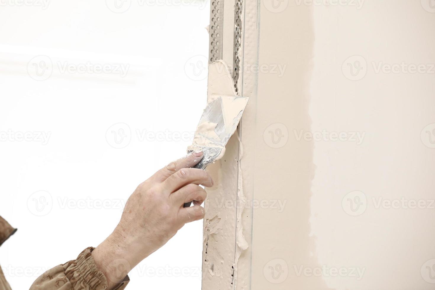 Builder using a trowel to add plaster. Plastering wall with putty-knife, close up image. Fixing wall surface and preparation for painting. construction work during quarantine photo