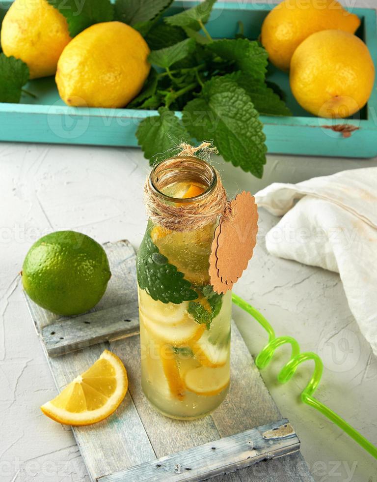 bebida limonada en un vaso botella y maduro Fresco limones foto