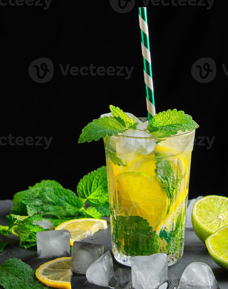 refreshing drink lemonade with lemons, mint leaves, ice cubes and lime in a glass photo