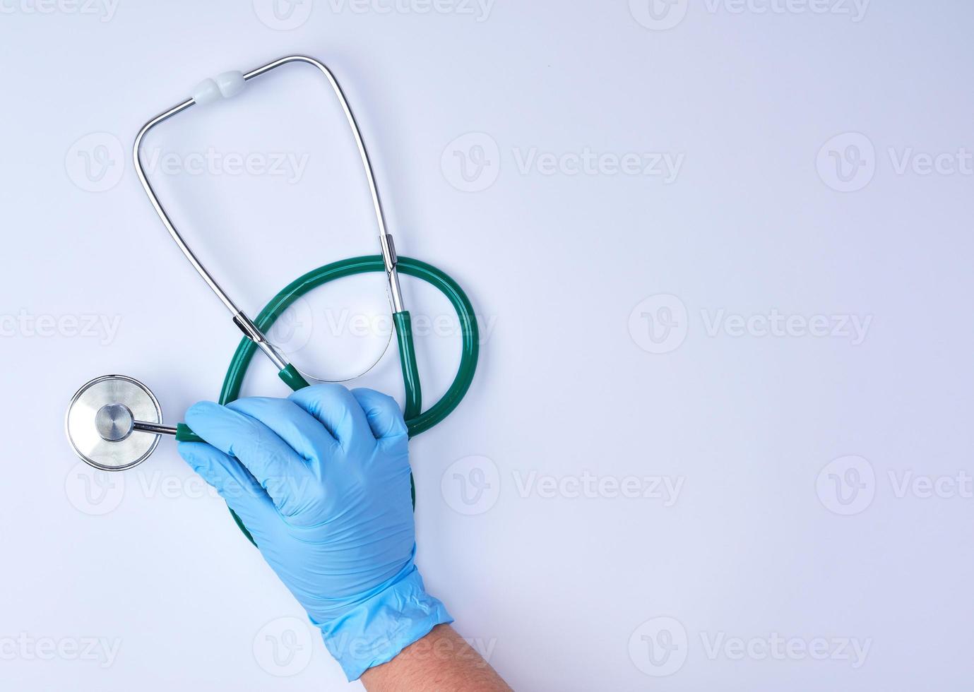 human hand in blue latex sterile gloves holding a medical stethoscope photo
