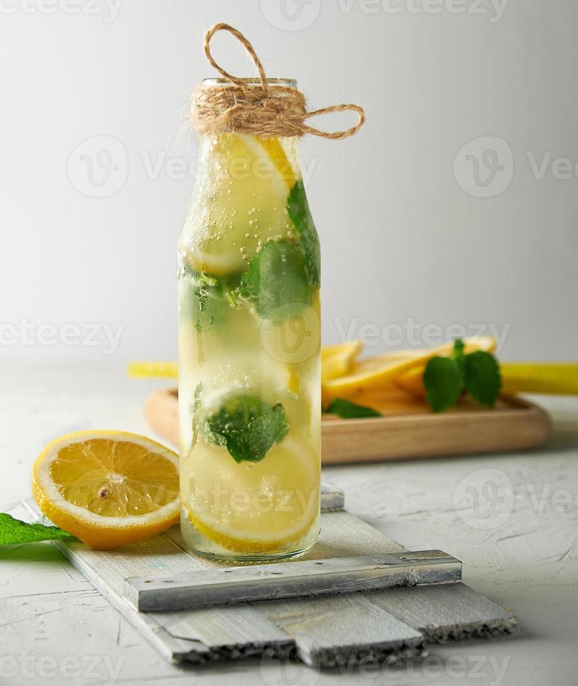 summer refreshing drink lemonade with lemons, mint leaves, lime in a glass bottle photo