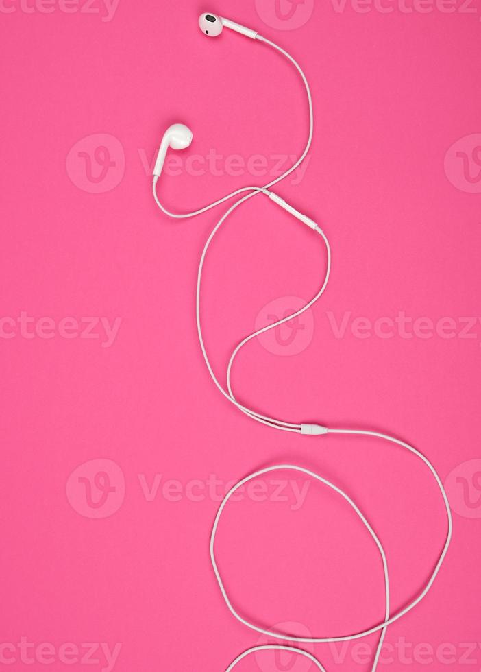 earphones with a white cable on a pink background photo