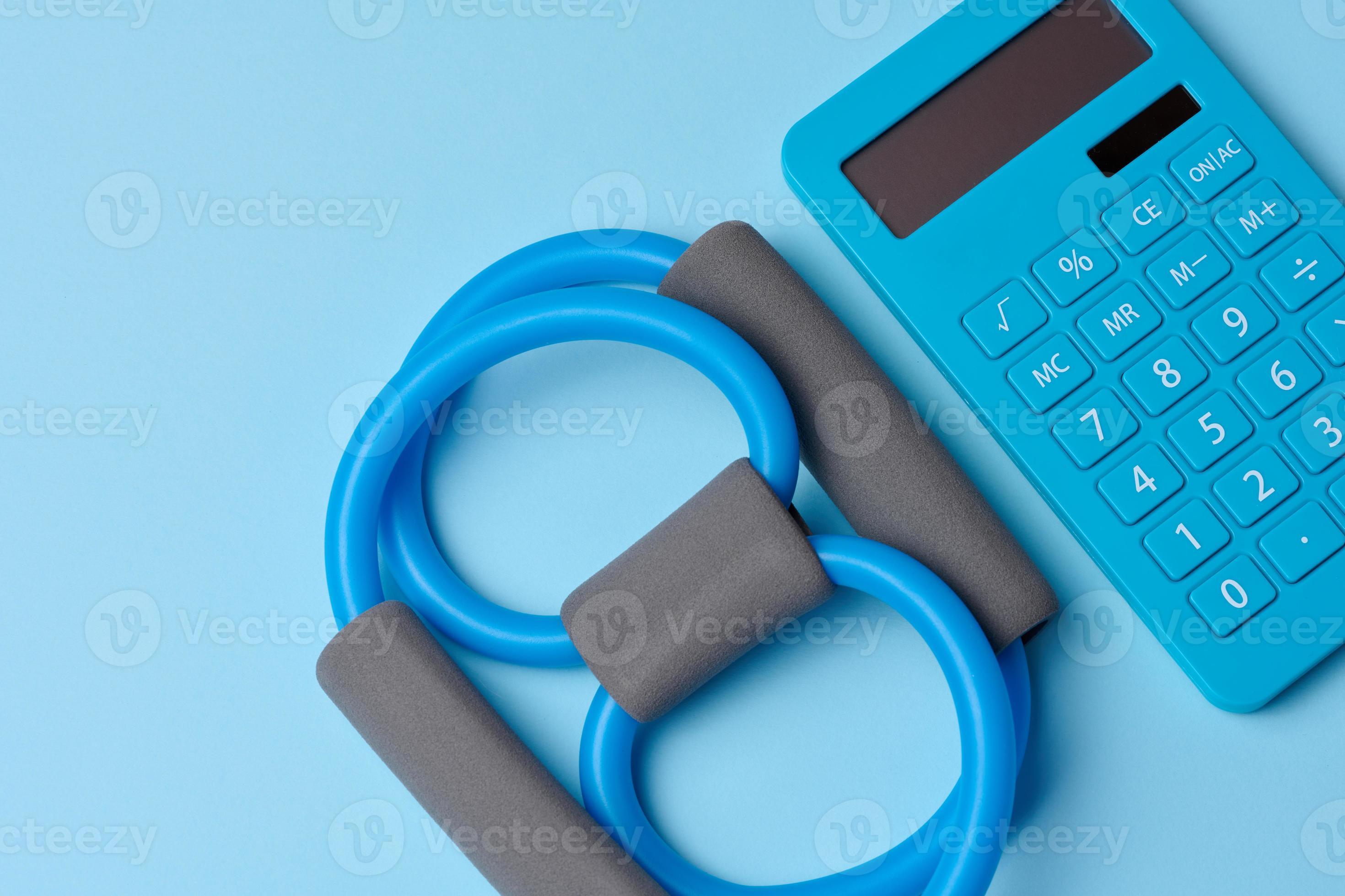 Rubber sports simulator expander and a calculator on a blue background, top view, calorie
