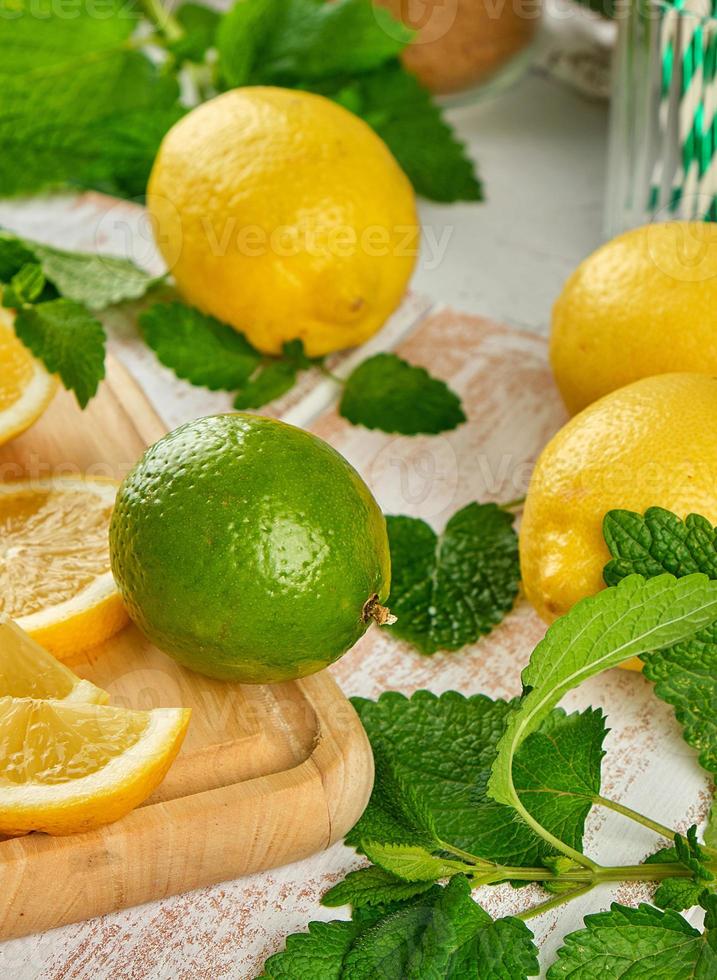 ripe yellow lemons and lime, mint green on a white wooden board photo