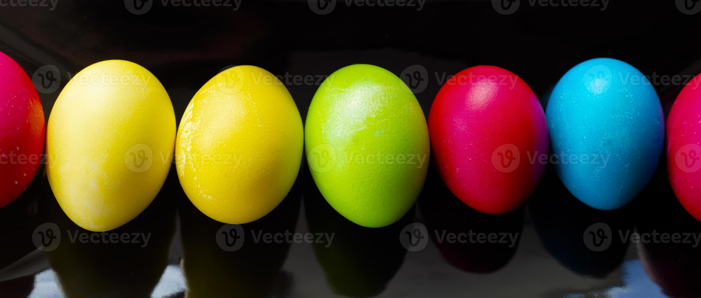 Easter multi-colored eggs in a row on a black rectangular dish. photo