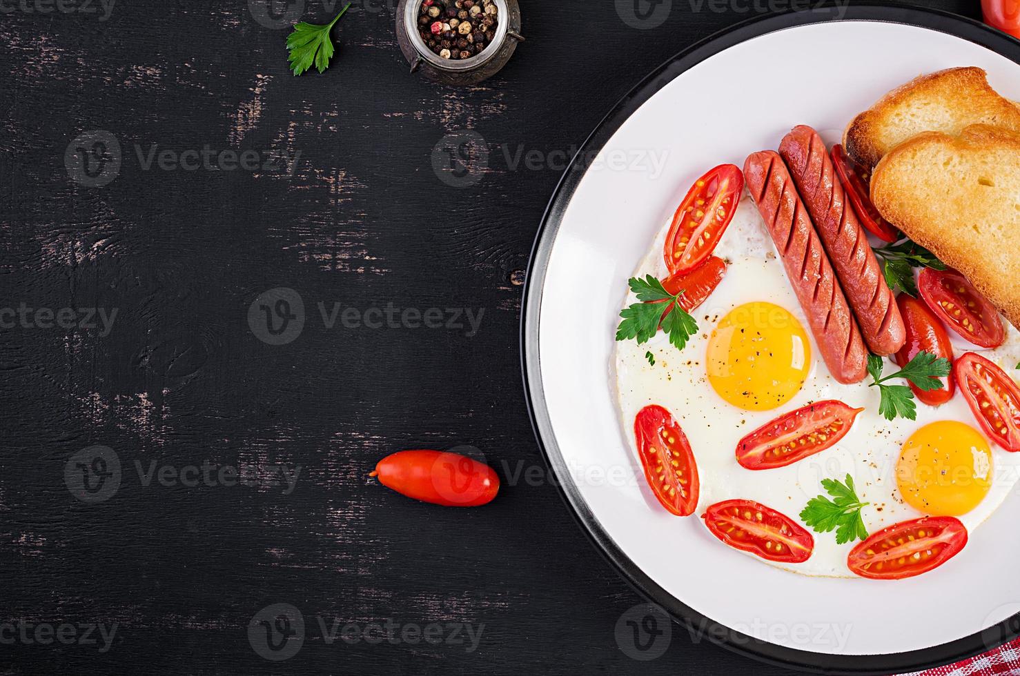 English breakfast - fried egg,  tomatoes, sausage,  and toasts. Top view, overhead photo