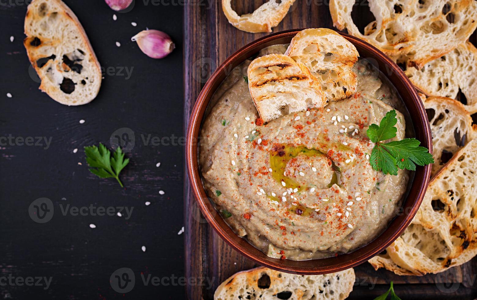 Baba ghanoush vegan hummus from eggplant with seasoning, parsley and toasts. Baba ganoush. Middle Eastern cuisine. Top view, overhead photo